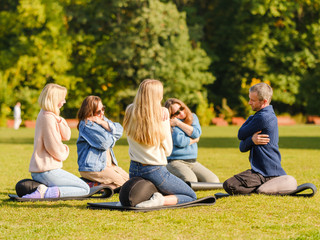 Fototapeta premium A group of young people meditate outdoors in a park. 