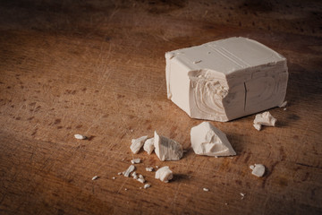 A stick of fresh yeast (brewer's yeast), used for bread and pizza doughs, on a wooden cutting board