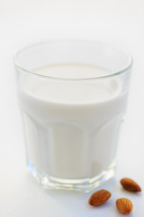 Almond milk in a glass on a light background. Lactose free milk.