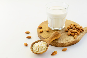 Almond flour in a bowl with a glass of almond milk on a wooden board. Healthy food concept. Horizontal orientation, copy space.