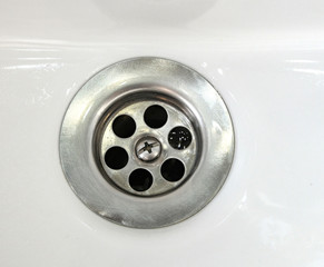 Draining water with a stainless steel grate in an old, long-used bathroom sink