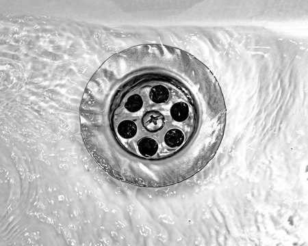 Draining water with a stainless steel grate in an old, long-used bathroom sink