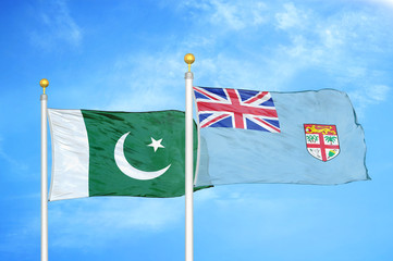 Pakistan and Fiji two flags on flagpoles and blue cloudy sky