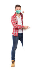 Young man wearing face mask is standing behind white banner and pointing