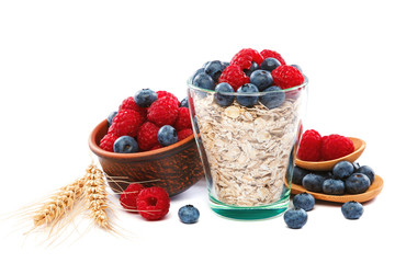 Fresh blueberries and raspberries, oatmeal in a bowl with a wooden spoon