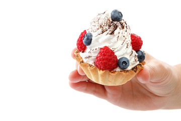 Fresh blueberries and raspberries in a cream cake in a female hand