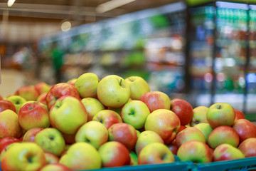 red and green apples in boxes in the store, against the background of buyers