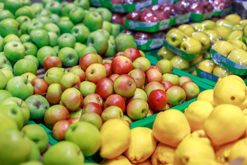 green, yellow and red apples on a counter in a store