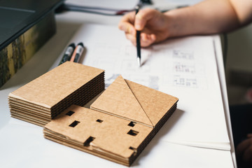 Architect Desk With Cardboard Architectural Model and Architect Hand Drawing Sketches. Selective...