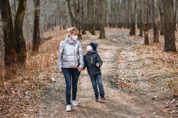Fototapeta premium A girl with her son in sanitary masks on a walk in the Park