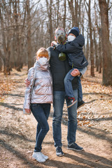 Fototapeta premium A small family in sanitary masks on a walk in the Park. People walk in the conditions of the quarantine