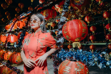 Fototapeta premium A beautiful asian woman on modern Chinese traditional dress standing at front of red lantern for Chinese new year.