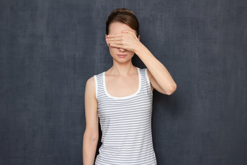 Girl is covering her eyes with hand, not wanting to look at something