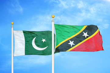 Pakistan and Saint Kitts and Nevis two flags on flagpoles and blue cloudy sky