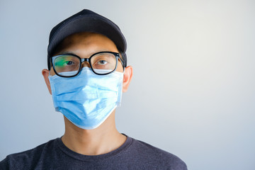 Head shot of asian male wearing hat and surgical face mask before going out from home quarantine to prevent virus spread and infection.