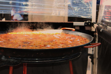 A sizzling paella being cooked by a vendor in a tent at a street fair. Australia