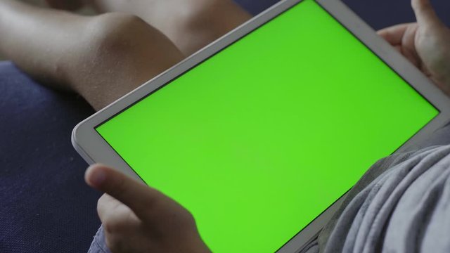 close up of touchpad or tablet green screen with child watching online content