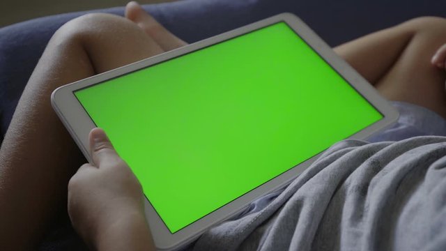 Close up of tablet or touchpad with green screen being used by child or kid