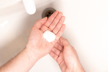 Man washing hands in over white sink