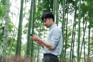 A young Asian male is walking in the bamboo forest