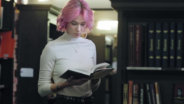 Modern stylish woman holds a book in library or bookstore.