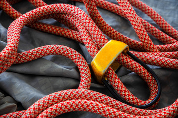 Yellow ATC belay device with red orange dynamic climbing rope