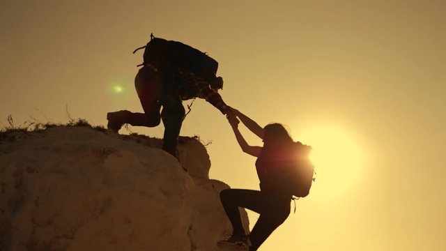 Happy family. Team work in business and life. A man holds out a helping hand to a girl while climbing to a height. The path to success and victory. Team Success Concept