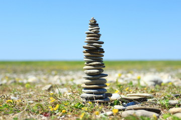 Rock balancing, stone stacks on the beach, blue sky in background