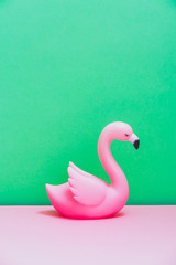 Plastic flamingo ion pink and green background. Still life and minimal. Hot summer vacation concept.