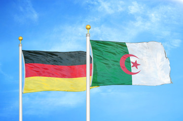 Germany and Algeria two flags on flagpoles and blue cloudy sky