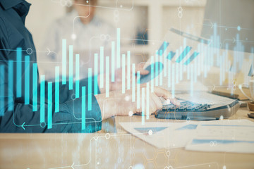 Double exposure of graph with man typing on computer in office on background. Concept of hard work. Closeup.