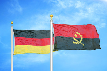 Germany and Angola two flags on flagpoles and blue cloudy sky
