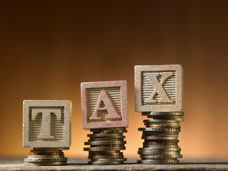 Tax Concept with wooden block on stacked coins