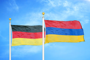 Germany and Armenia two flags on flagpoles and blue cloudy sky