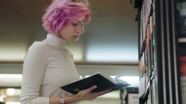 Stylish woman turns the pages of a book in a bookstore.