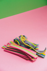 Many rainbow chewable candy gums on pink and green background. Tasty treats in minimal art.