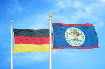 Germany and Belize two flags on flagpoles and blue cloudy sky