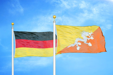 Germany and Bhutan two flags on flagpoles and blue cloudy sky