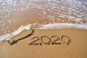 the wave washes away the heart drawn in the sand and the inscription 2020
