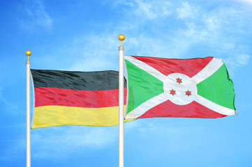 Germany and Burundi two flags on flagpoles and blue cloudy sky