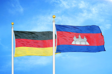Germany and Cambodia two flags on flagpoles and blue cloudy sky