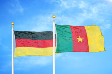 Germany and Cameroon two flags on flagpoles and blue cloudy sky