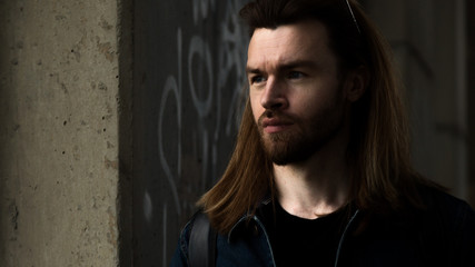 Portrait of a young handsome man. Long brown hair, beard, blue eyes, 30 years old.