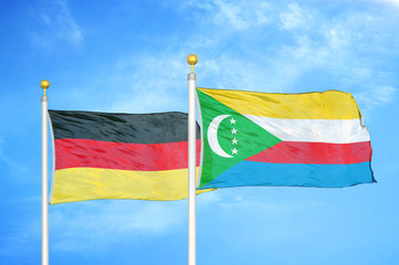 Germany and Comoros two flags on flagpoles and blue cloudy sky