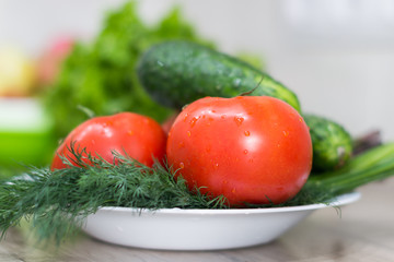 Fresh tomatoes, cucumbers and dill on a dish.