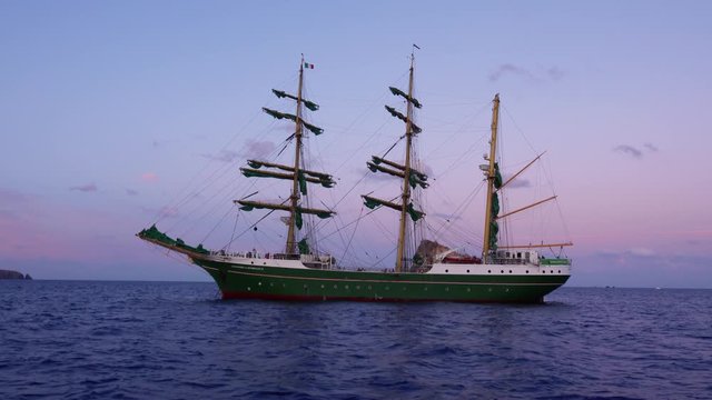 Green sailing ship with folded sails is floating in sea. Lipari Islands, Sicily, Italy