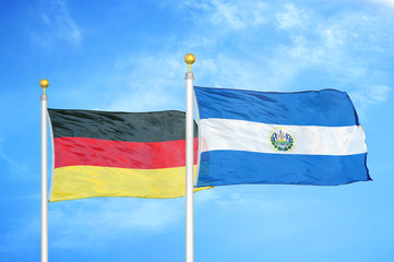 Germany and El Salvador two flags on flagpoles and blue cloudy sky