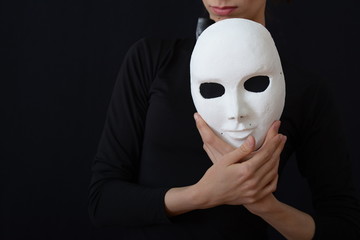 A girl actress holds a white theatrical mask in her hands