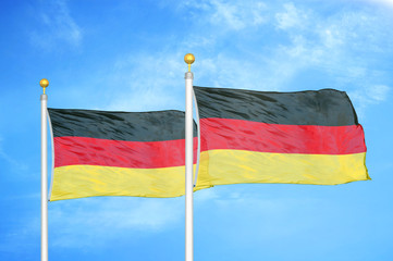 Germany two flags on flagpoles and blue cloudy sky