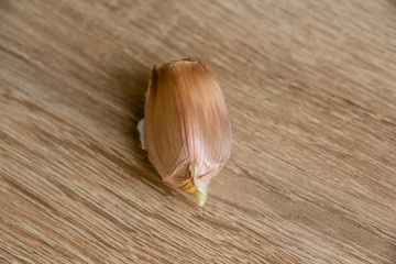 one clove of garlic on a wooden background close-up